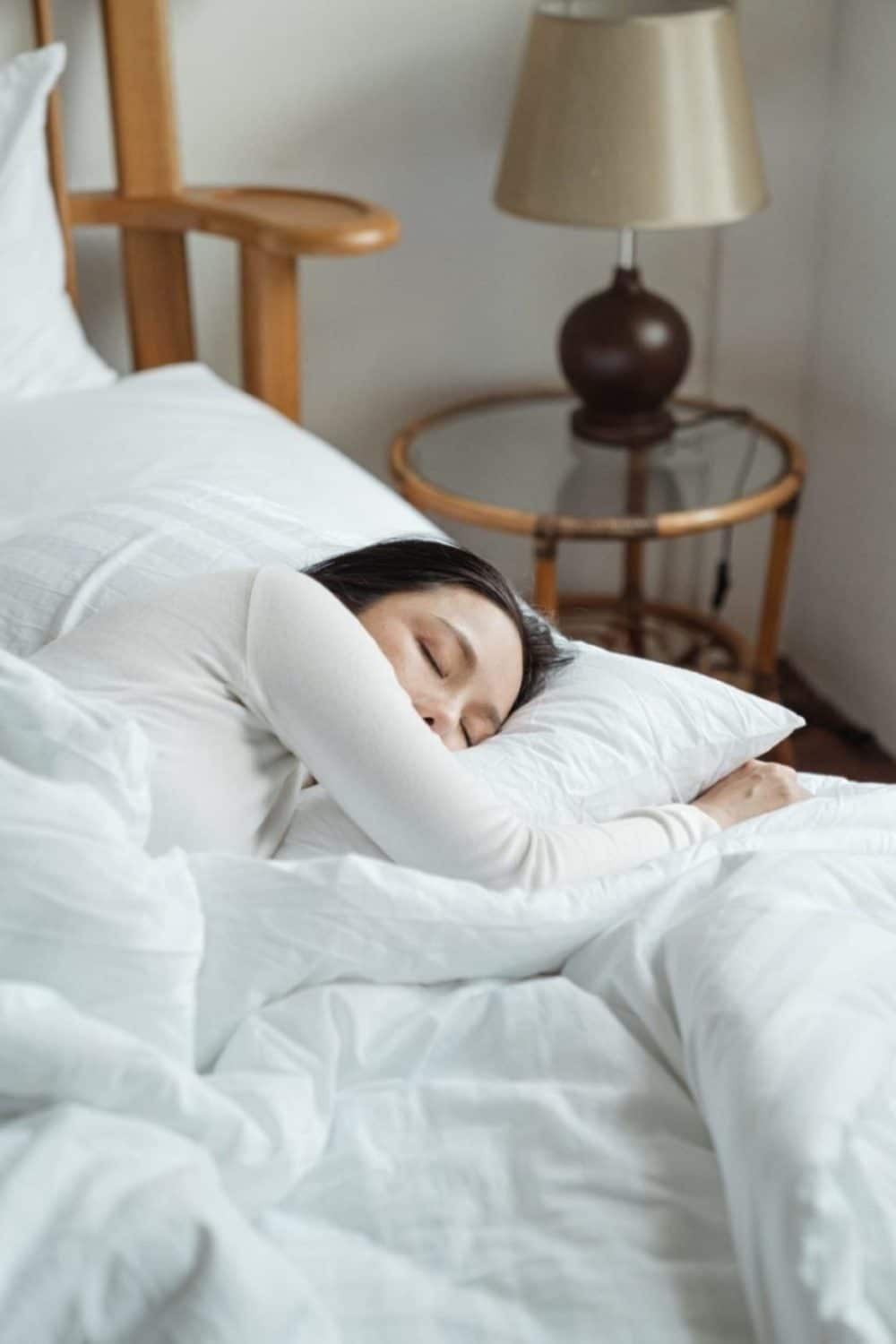 Eine schwangere Frau schläft in einem weißen Bett mit weißen Laken.