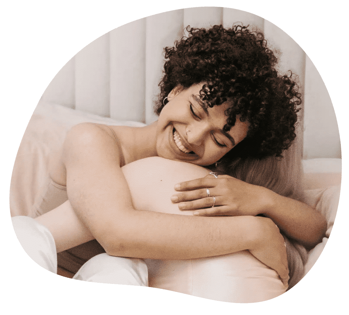 Zwei Frauen umarmen sich im Bett.